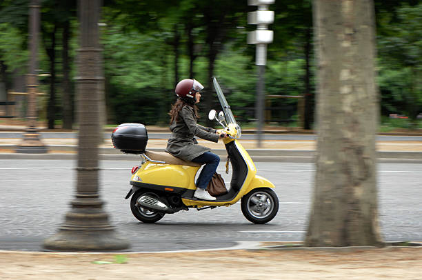 A woman riding a yellow motorcycle