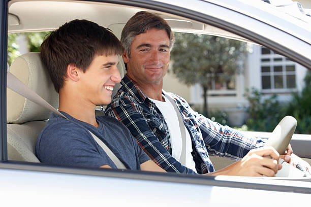 A driver smiling, his instructor looking at him
