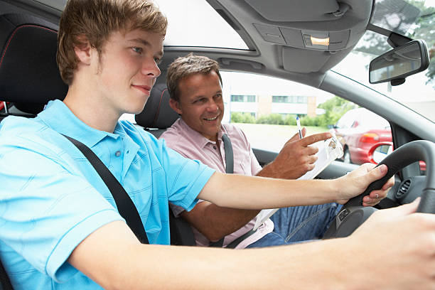 A male instructor smiling while teaching a beginner driver