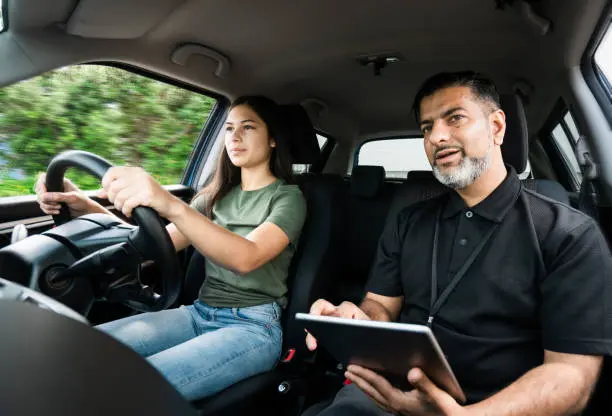 Young girl taking lessons for driving on the road in Auckland, New Zealand.