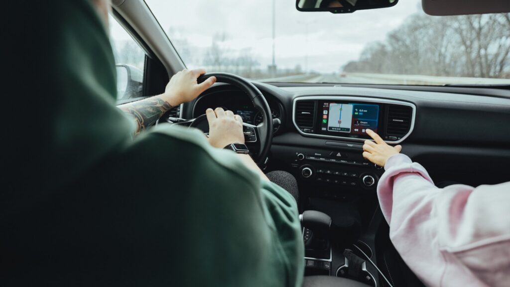 A man driving and a passenger choosing the music to play