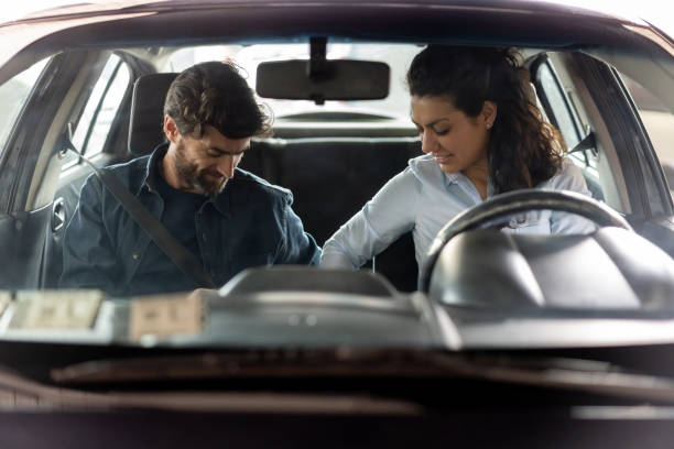 A female driver helping a male passenger in putting his seatbelt