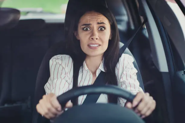 A woman driving and looking scared