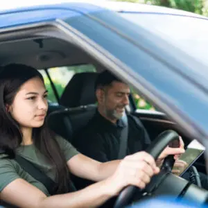 Young girl taking lessons for driving on the road