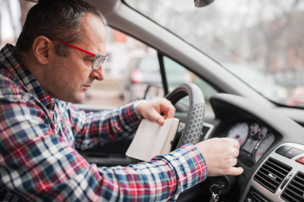 A man holding a notebook and checking his car