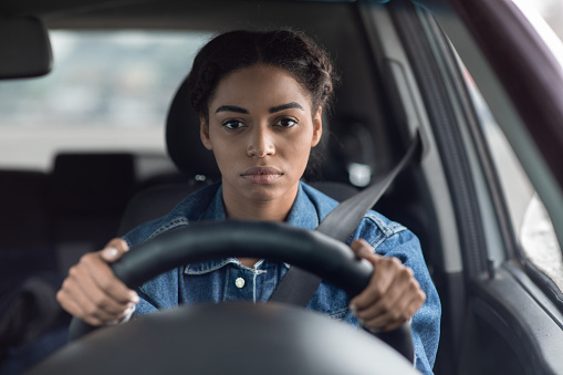 Traffic jams, routine commute, problems and tired driver. Sad sick upset millennial african american lady holds steering wheel and looks out windshield and waiting of motion on way, copy space
