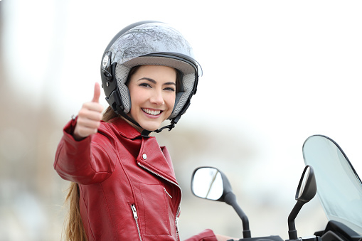 A woman in a motorcycle, doing a thumbs up